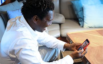 A man sitting inside a superyacht using internet for yachts on his smart phone to video chat.